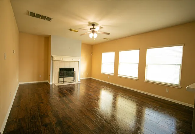 a view of an empty room with window and wooden floor