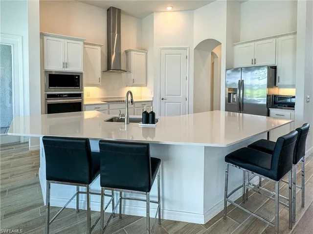 a kitchen with stainless steel appliances a dining table chairs microwave and sink