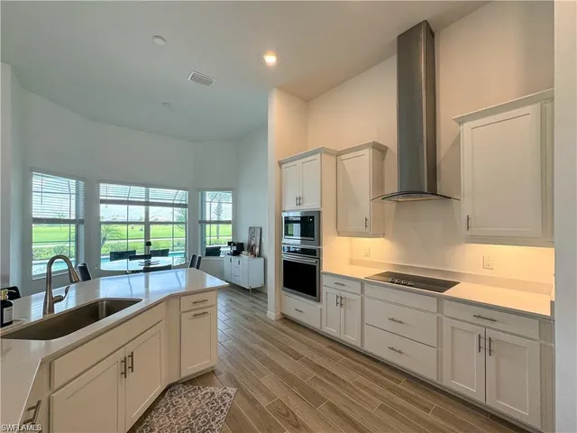a kitchen with stainless steel appliances white cabinets a sink and a large window