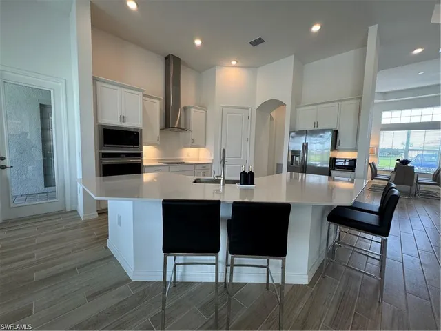 a kitchen with stainless steel appliances kitchen island granite countertop a table and chairs in it