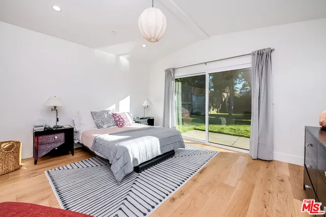 a spacious bedroom with a bed and wooden floor