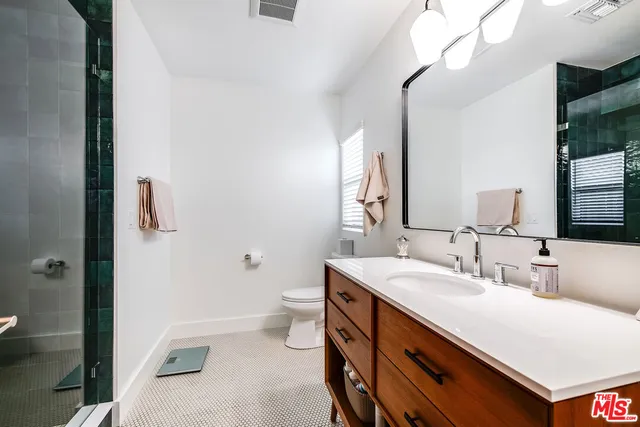 a bathroom with a sink a toilet a mirror and shower