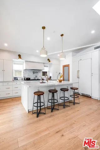 a open kitchen with stainless steel appliances kitchen island granite countertop a table chairs and a refrigerator