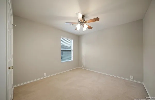 an empty room with a window and a fan