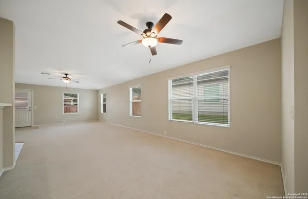 an empty room with a ceiling fan and window