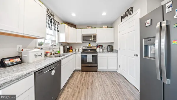 a kitchen with stainless steel appliances granite countertop a refrigerator a stove top oven a sink and dishwasher with wooden floor