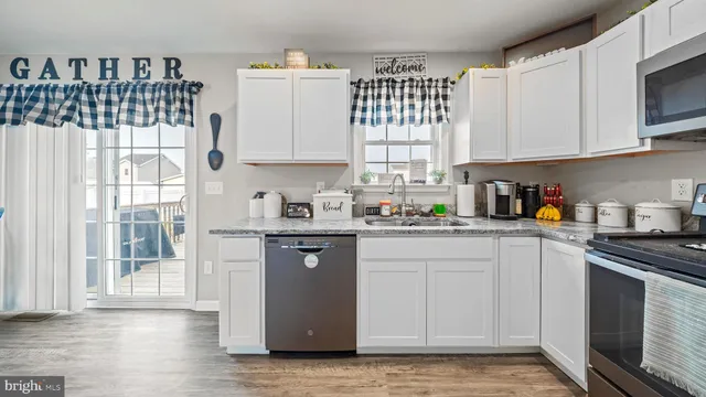 a kitchen with granite countertop white cabinets and white appliances