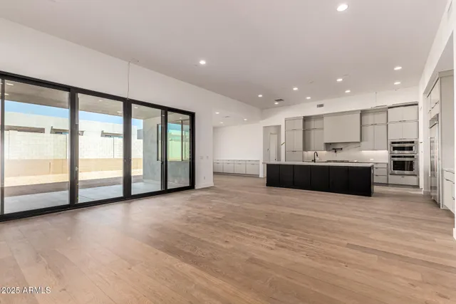 a view of an empty room with kitchen view and a large window