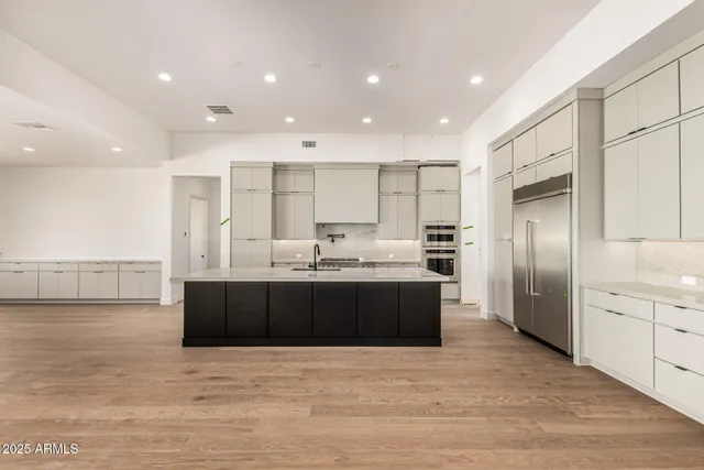 a large kitchen with stainless steel appliances kitchen island granite countertop a large counter top and a stove top oven