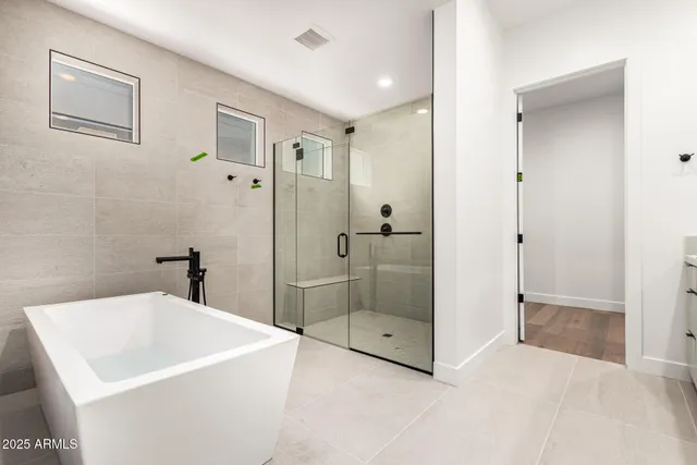 a bathroom with a tub a shower and mirror