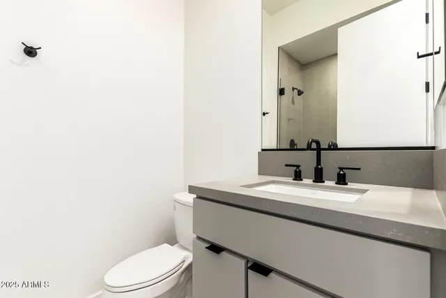 a bathroom with a granite countertop sink mirror a toilet and a mirror