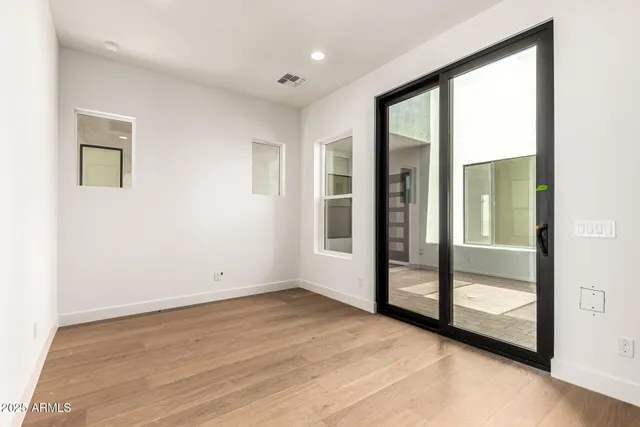 an empty room with wooden floor and windows