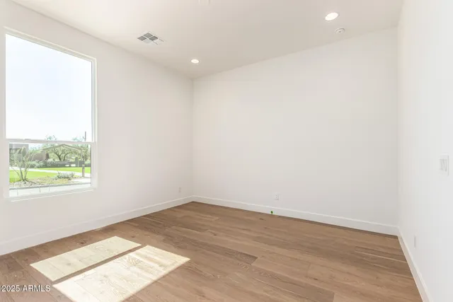 an empty room with wooden floor and windows