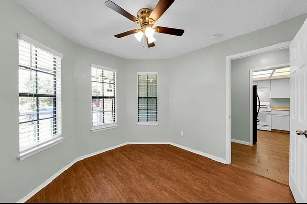 a view of empty room with wooden floor and fan