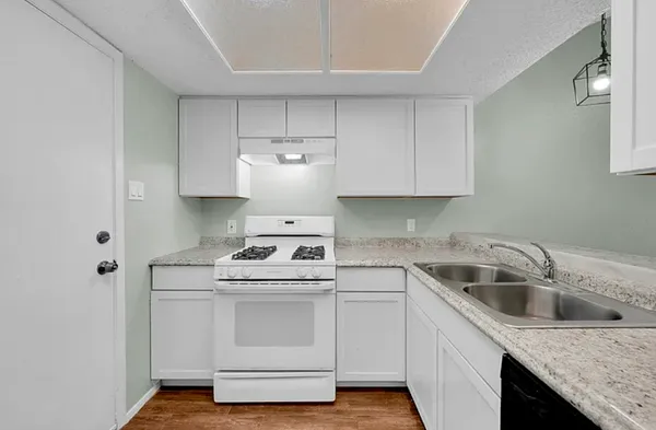 a kitchen with granite countertop white cabinets sink and stove