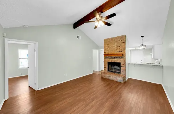 an empty room with wooden floor fireplace and windows