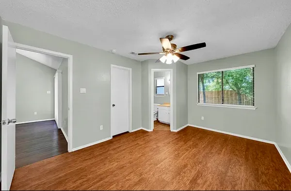 a view of empty room with wooden floor and fan