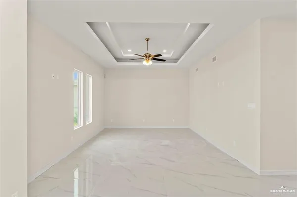 an empty room with windows and ceiling fan