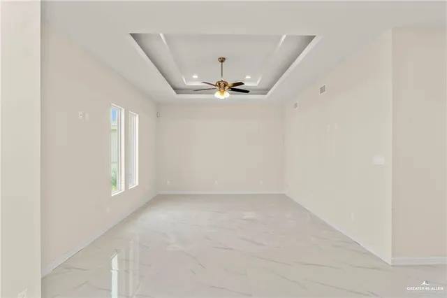 an empty room with windows and ceiling fan