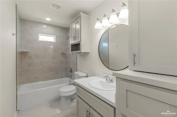 a bathroom with a granite countertop toilet a sink and a mirror