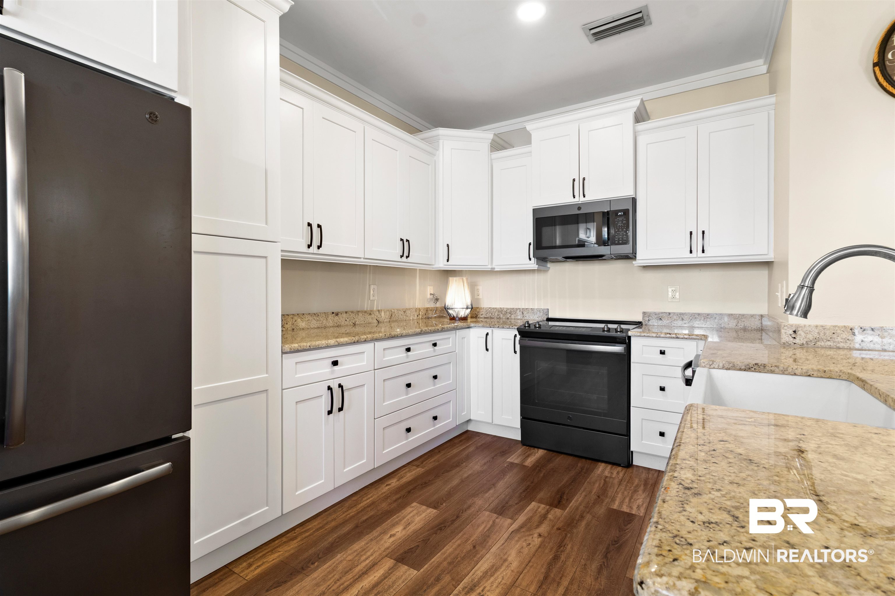 3543 Bayou Road, Unit 5 Orange Beach, AL 36561 - Photo 7 of 33 Modern kitchen featuring wood-finish flooring, white shaker cabinetry, granite countertops, and black appliances