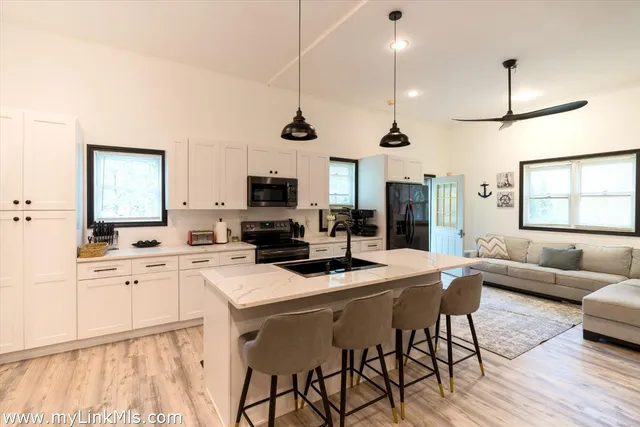 a kitchen with stainless steel appliances kitchen island granite countertop a stove a sink a dining table and chairs with wooden floor