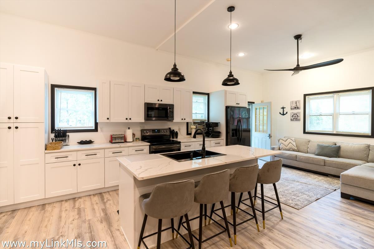 2 Farm Path Road Oak Bluffs, MA 02557 - Photo 32 of 37 a kitchen with stainless steel appliances kitchen island granite countertop a stove a sink a dining table and chairs with wooden floor