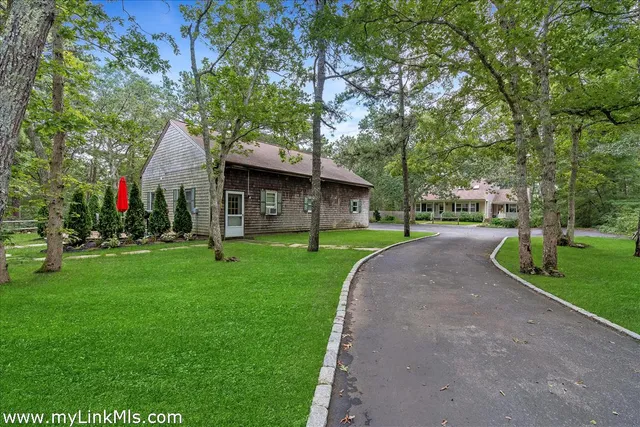 a view of a house with a big yard and large tree