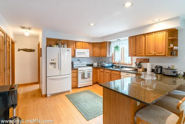 a kitchen with stainless steel appliances granite countertop a refrigerator a stove and a sink dishwasher with wooden floor