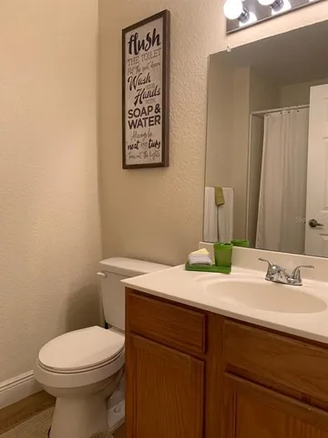 a bathroom with a granite countertop toilet sink and mirror