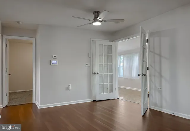 an empty room with a chandelier fan and windows