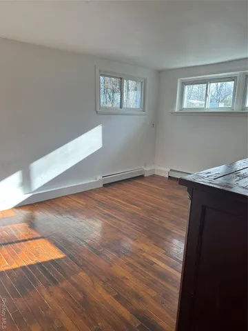 a view of empty room with window and wooden floor