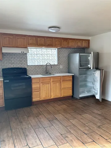 a view of kitchen with stainless steel appliances wooden floor and cabinets