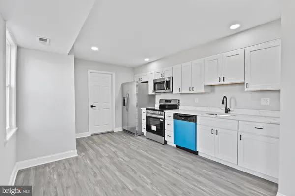 a kitchen with stainless steel appliances granite countertop a stove top oven a sink dishwasher and a refrigerator with wooden floor