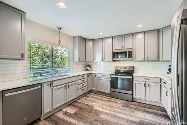 a kitchen with stainless steel appliances granite countertop white cabinets granite counter tops and a window