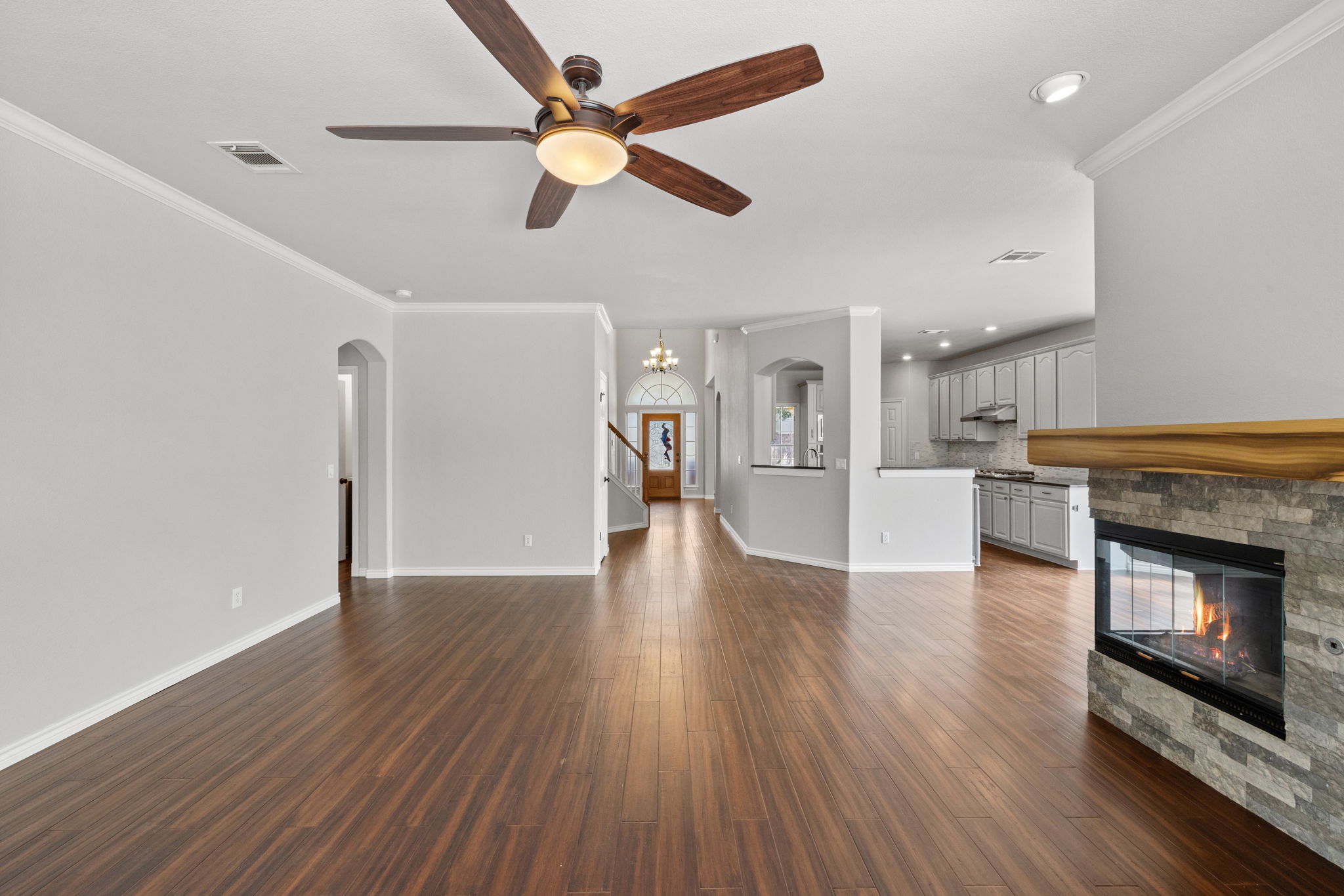 2211 Spring Hollow Path Round Rock, TX 78681 - Photo 18 of 36 Gleaming wood floors flow through this light-filled, open-concept living area with a stone fireplace.