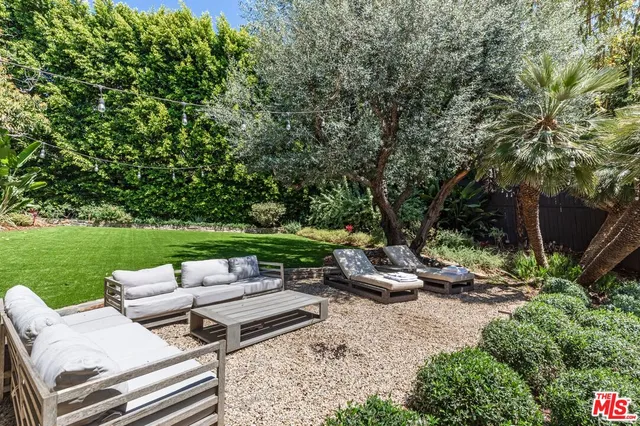 a view of a patio with lawn chairs and a dining table with chairs and a yard
