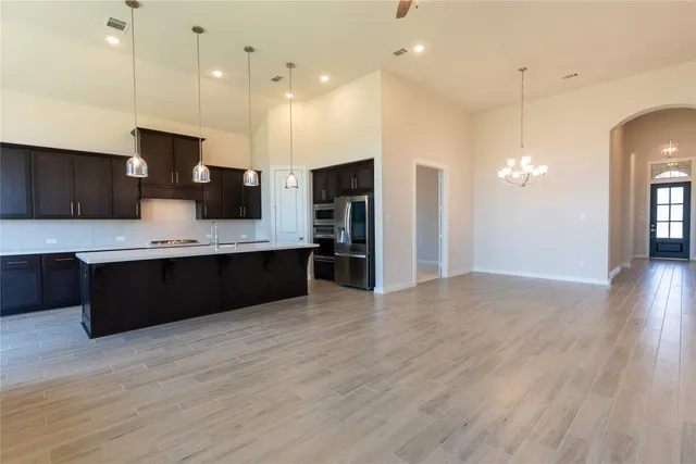 a large kitchen with a large counter top stainless steel appliances and wooden floor