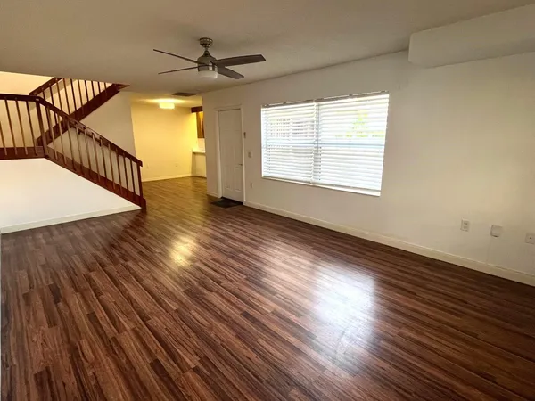 an empty room with wooden floor windows and a chandelier fan