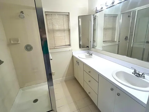 a bathroom with a double vanity sink mirror and shower