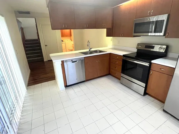 a kitchen with stainless steel appliances a sink a stove top oven a chimney and a window