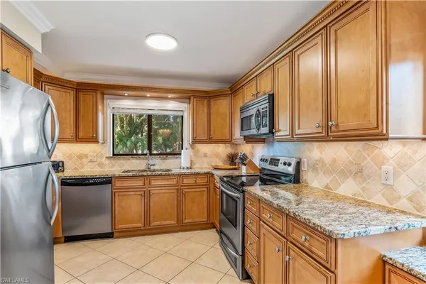 a kitchen with stainless steel appliances granite countertop a sink stove refrigerator and cabinets