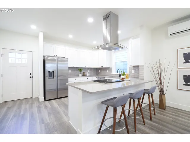 a kitchen with stainless steel appliances a table chairs refrigerator and wooden floor