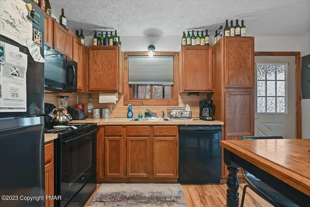a view of an empty room with window and hardwood floor