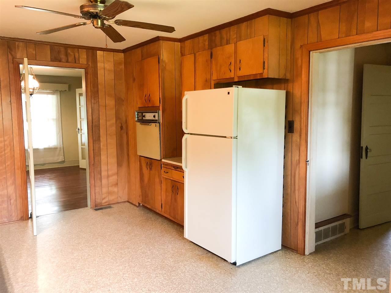 894 Shiloh Church Road Roxboro, NC 27574 - Photo 8 of 24 a view of a refrigerator in kitchen and an empty room with wooden floor