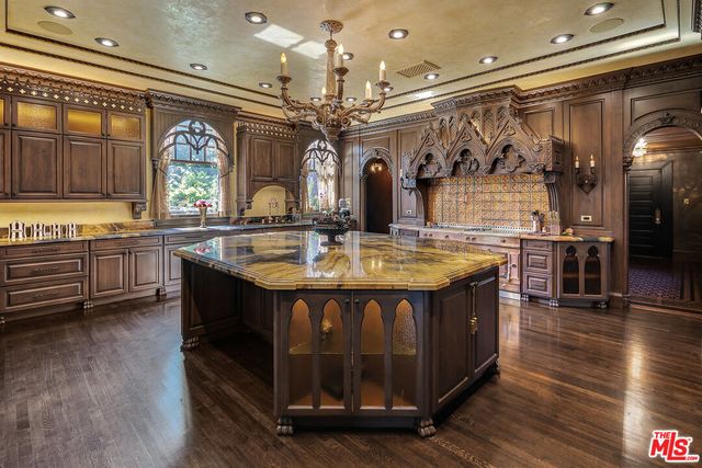 a view of living room kitchen with granite countertop stainless steel appliances stove and wooden floor