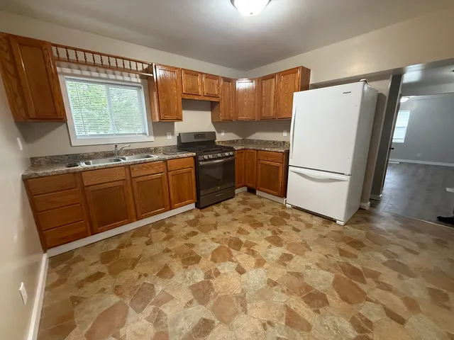 a kitchen with stainless steel appliances granite countertop a refrigerator sink and wooden cabinets