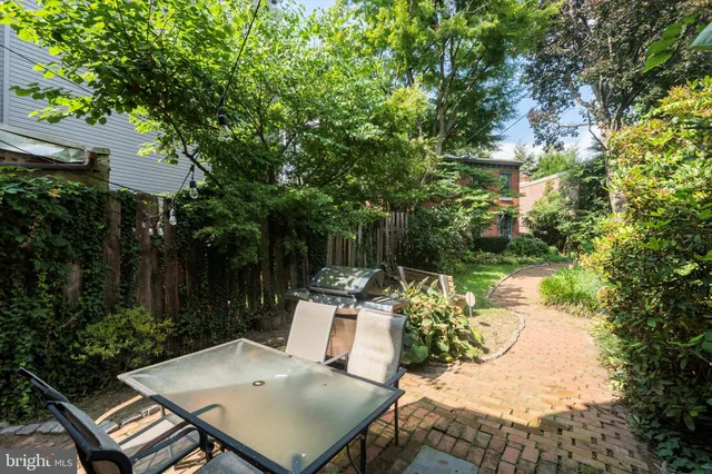 a view of a patio with table and chairs and potted plants with large trees