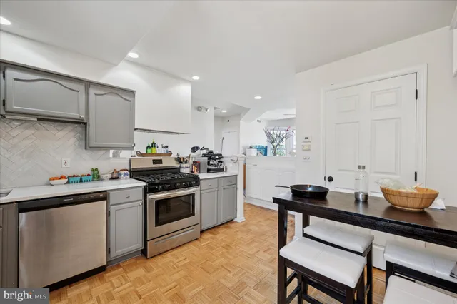 a kitchen with stainless steel appliances kitchen island granite countertop a stove a sink dishwasher and white cabinets with wooden floor