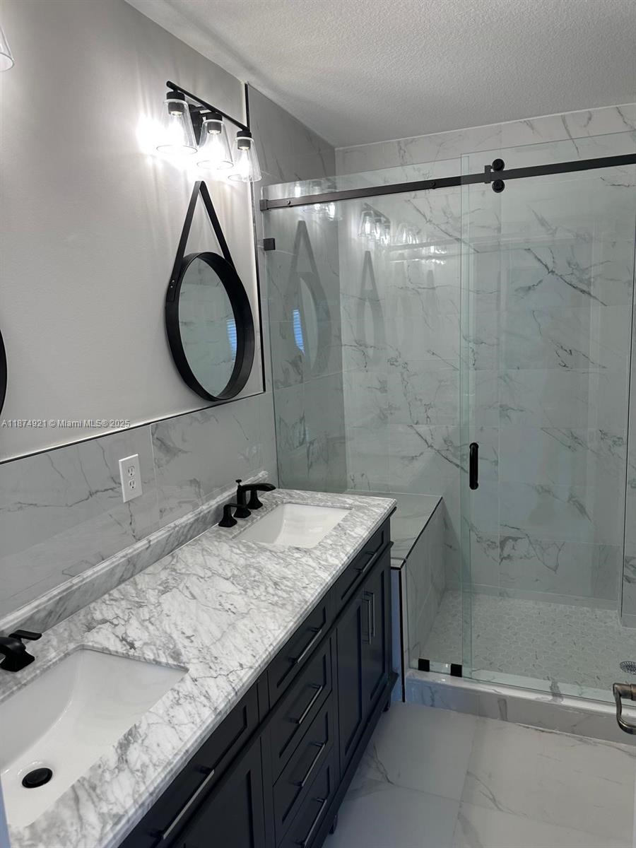 12421 Southwest 50th Court, Unit 337 Miramar, FL 33027 - Photo 43 of 46 a bathroom with a granite countertop sink a shower and a mirror